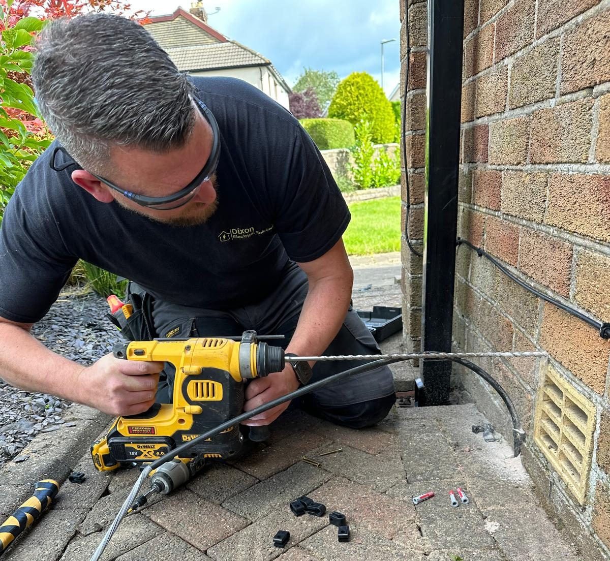 Steven Dixon drilling an exterior wall to run a dedicated SWA cable for a 7kW EV home charger install